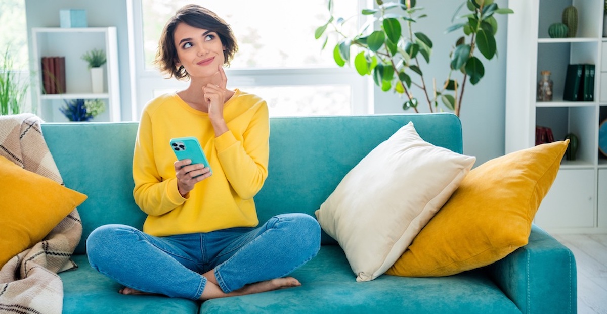 Woman in yellow jersey sitting on turquoise sofa.