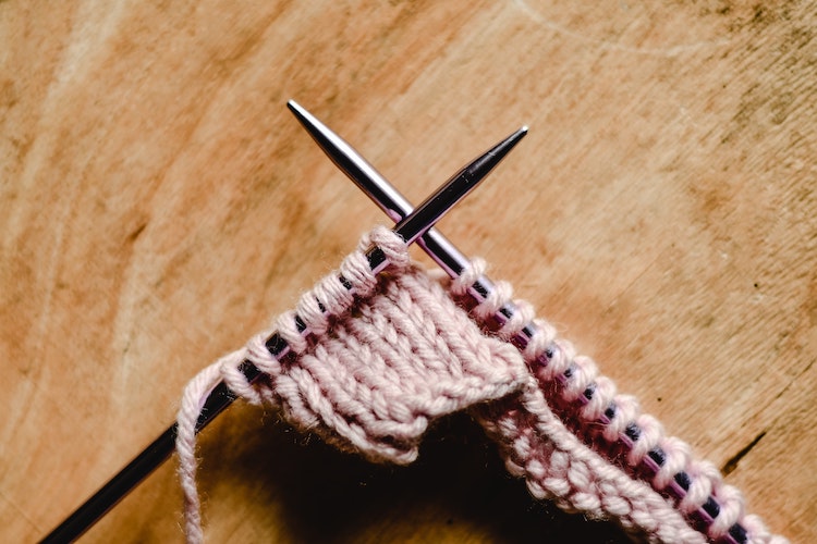 Pair of knitting needles with a few rows of plain knitting