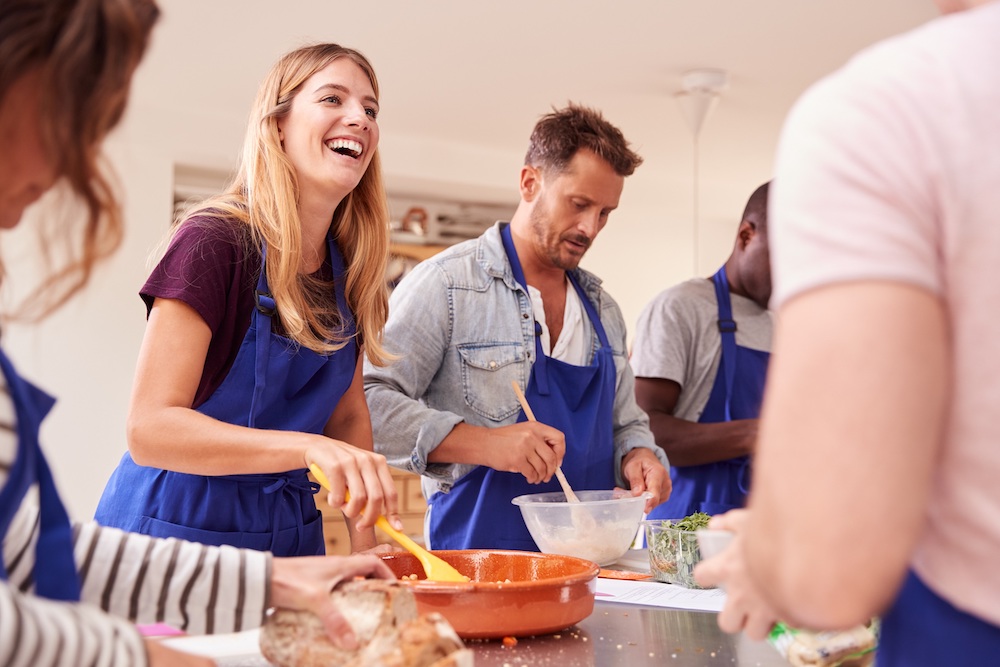 Group of young men and women cooking together and having fun.