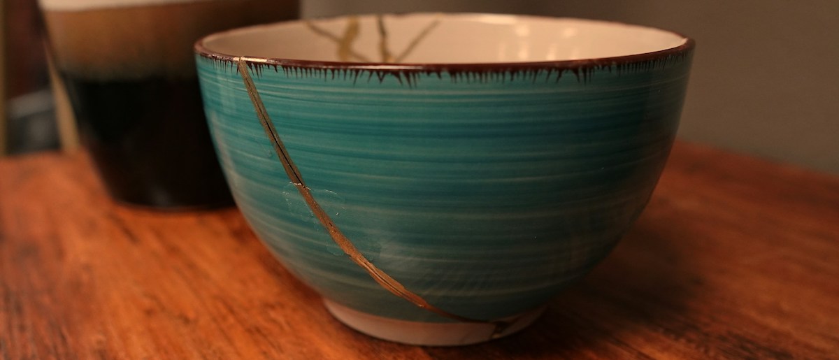 Green ceramic bowl repaired with gold kintsugi method
