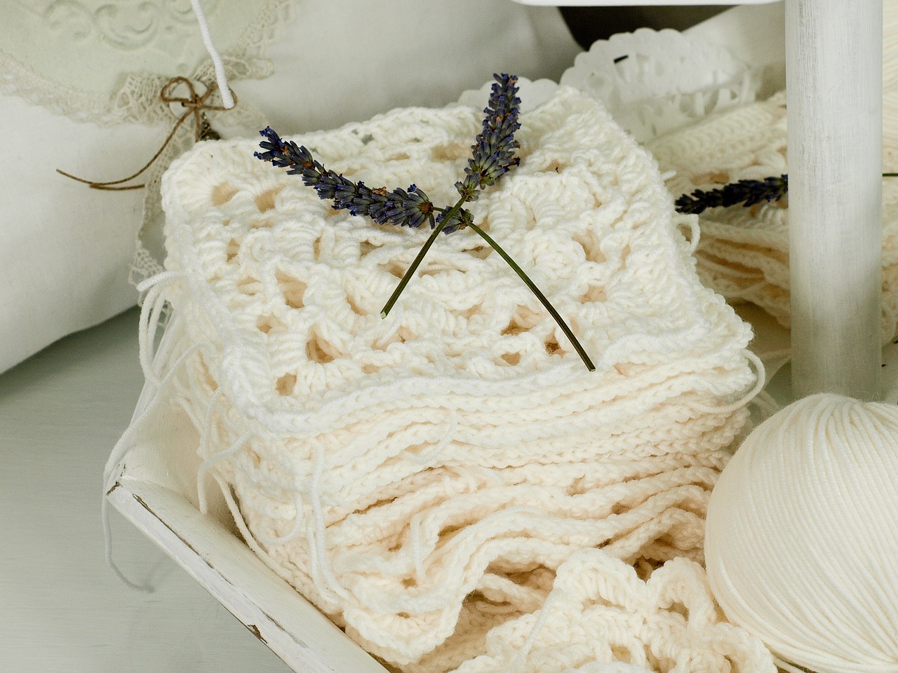 Pile of crocheted peggy squares in off-white colour